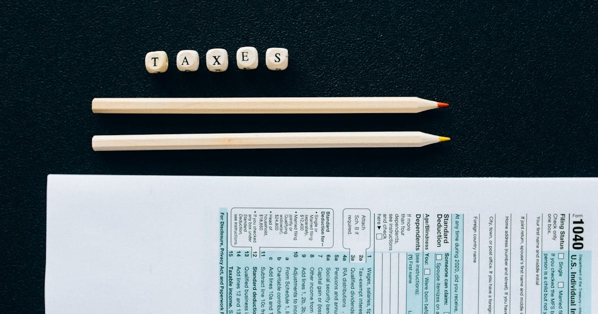 Messy desk with paper invoices, calculator, and a laptop showing spreadsheet chaos